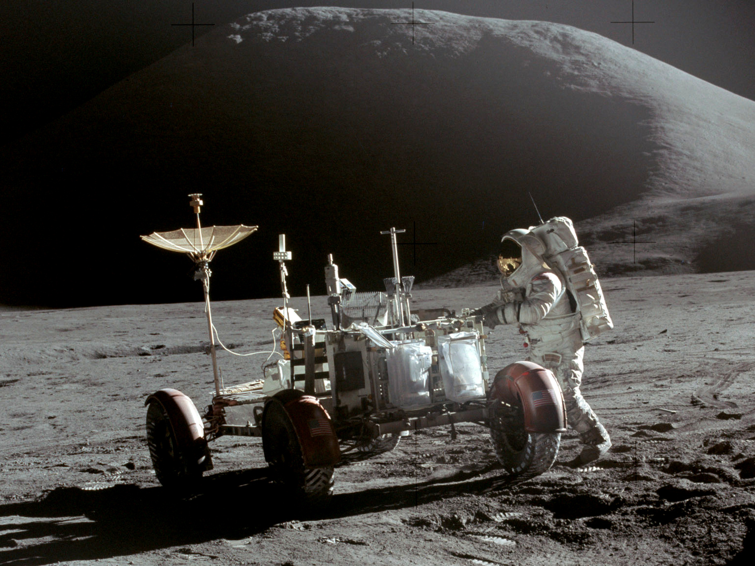 Apollo astronaut Jim Irwin beside the lunar rover on a rocky lunar surface.