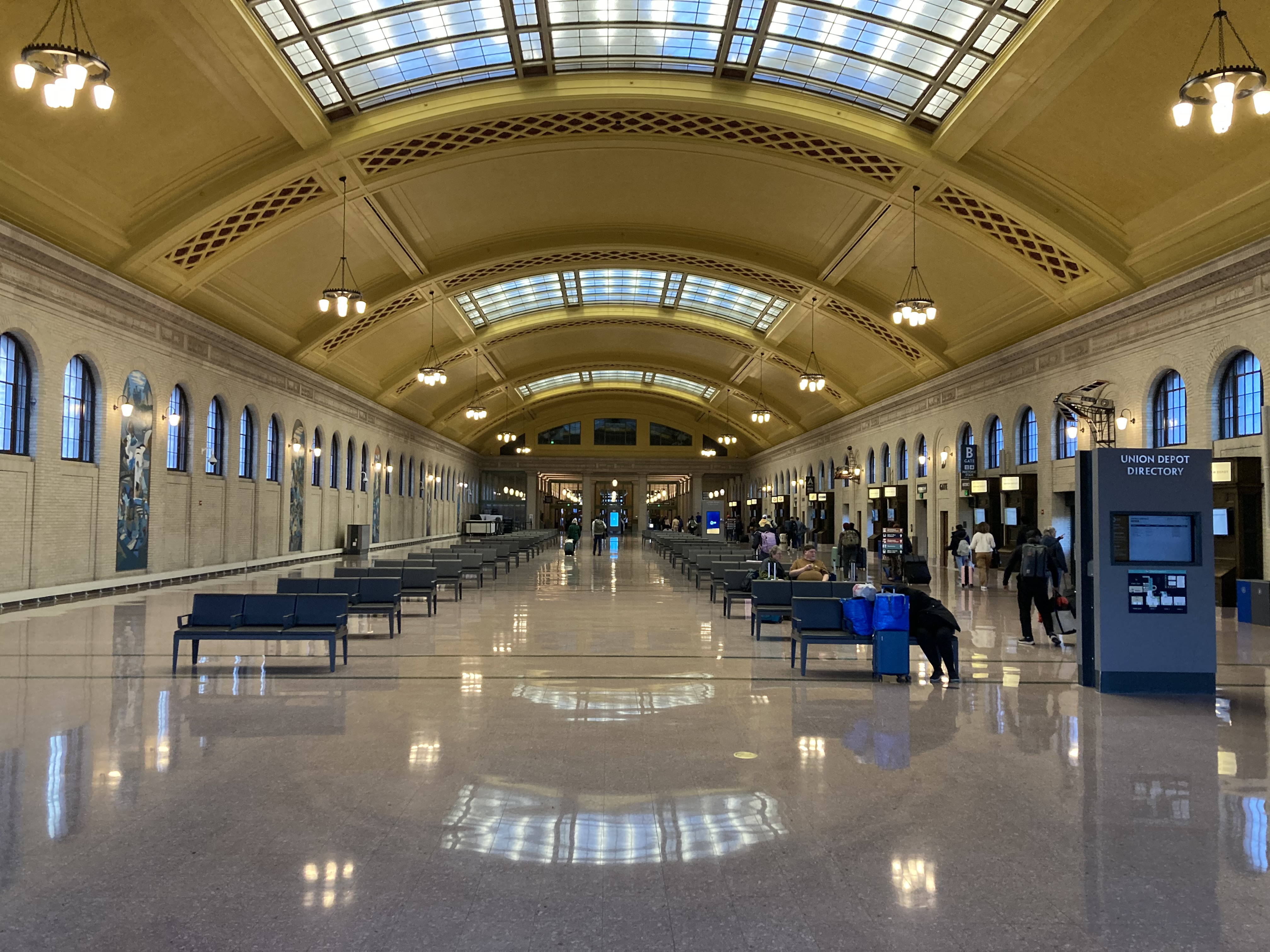 Benches and people inside Saint Paul Union Depot’s vaulted waiting hall.