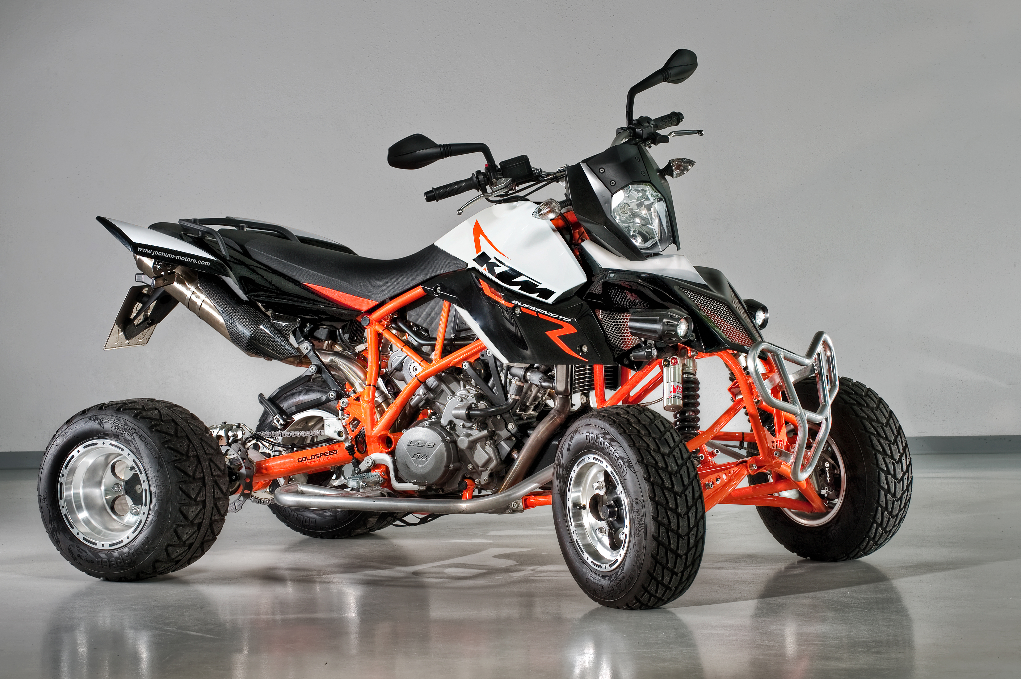 A custom-built four-wheel quad bike displayed on a grey floor.