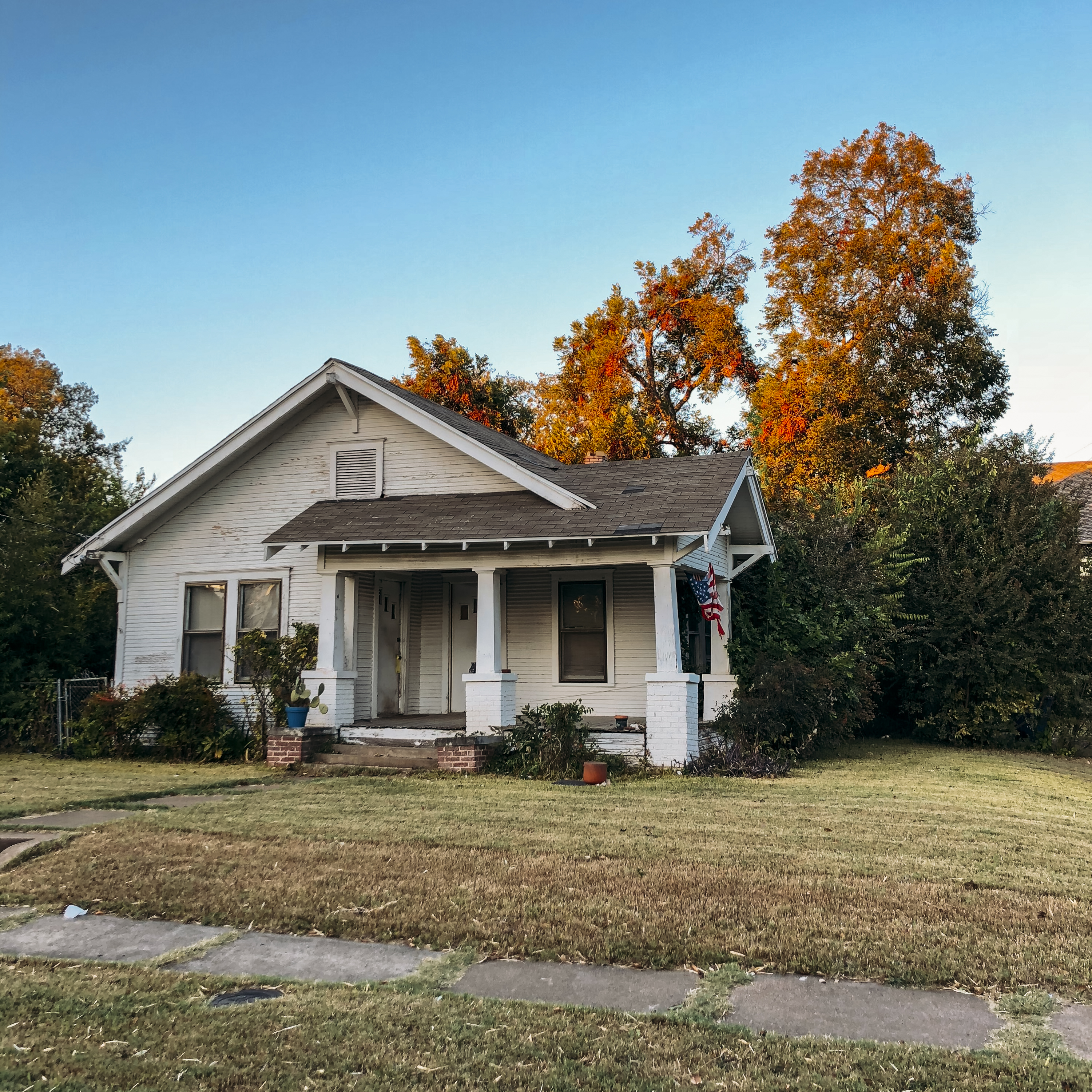 A white house with a front porch and autumn trees in Old East Dallas.