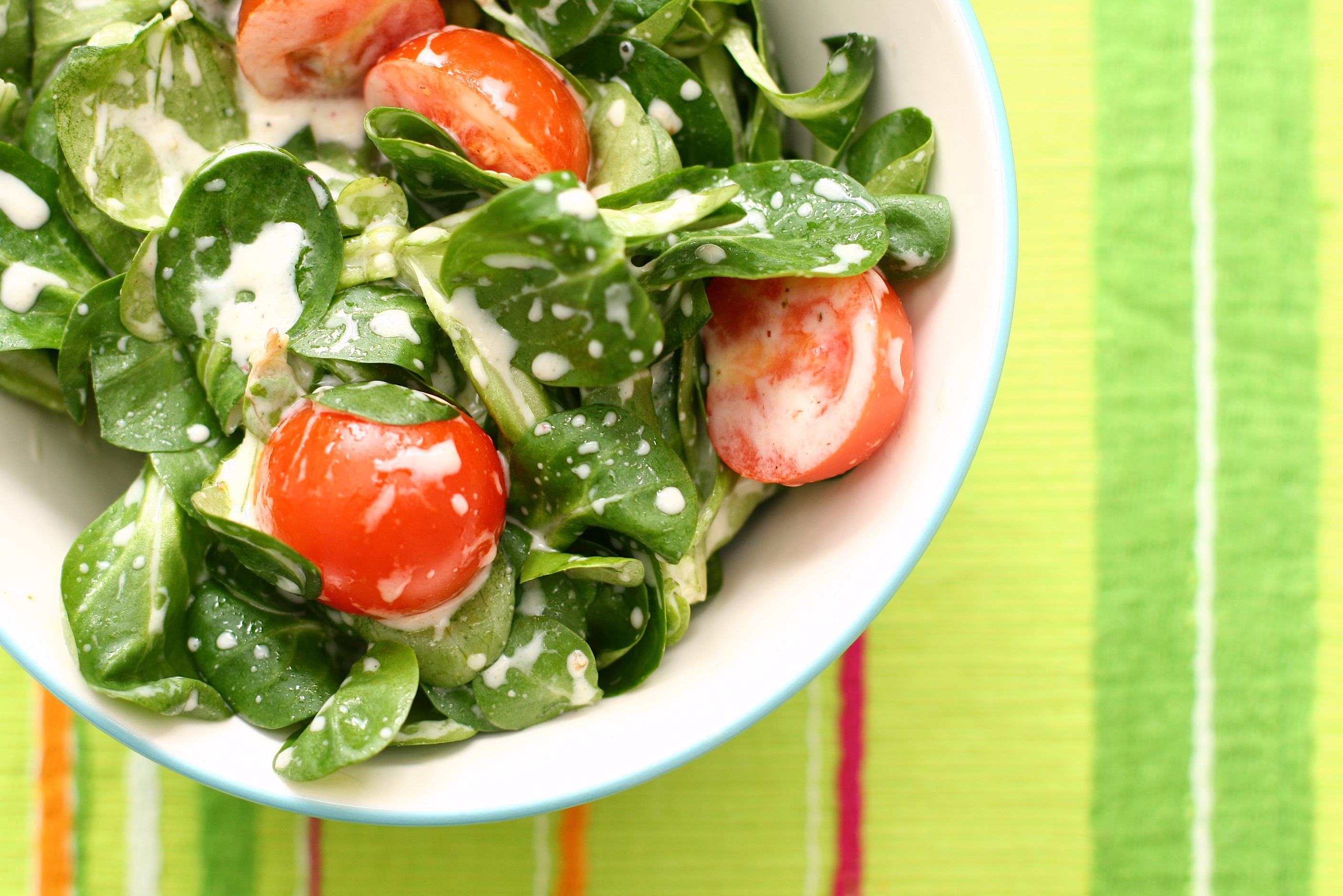 An archive bowl of green salad with tomatoes and dressing.