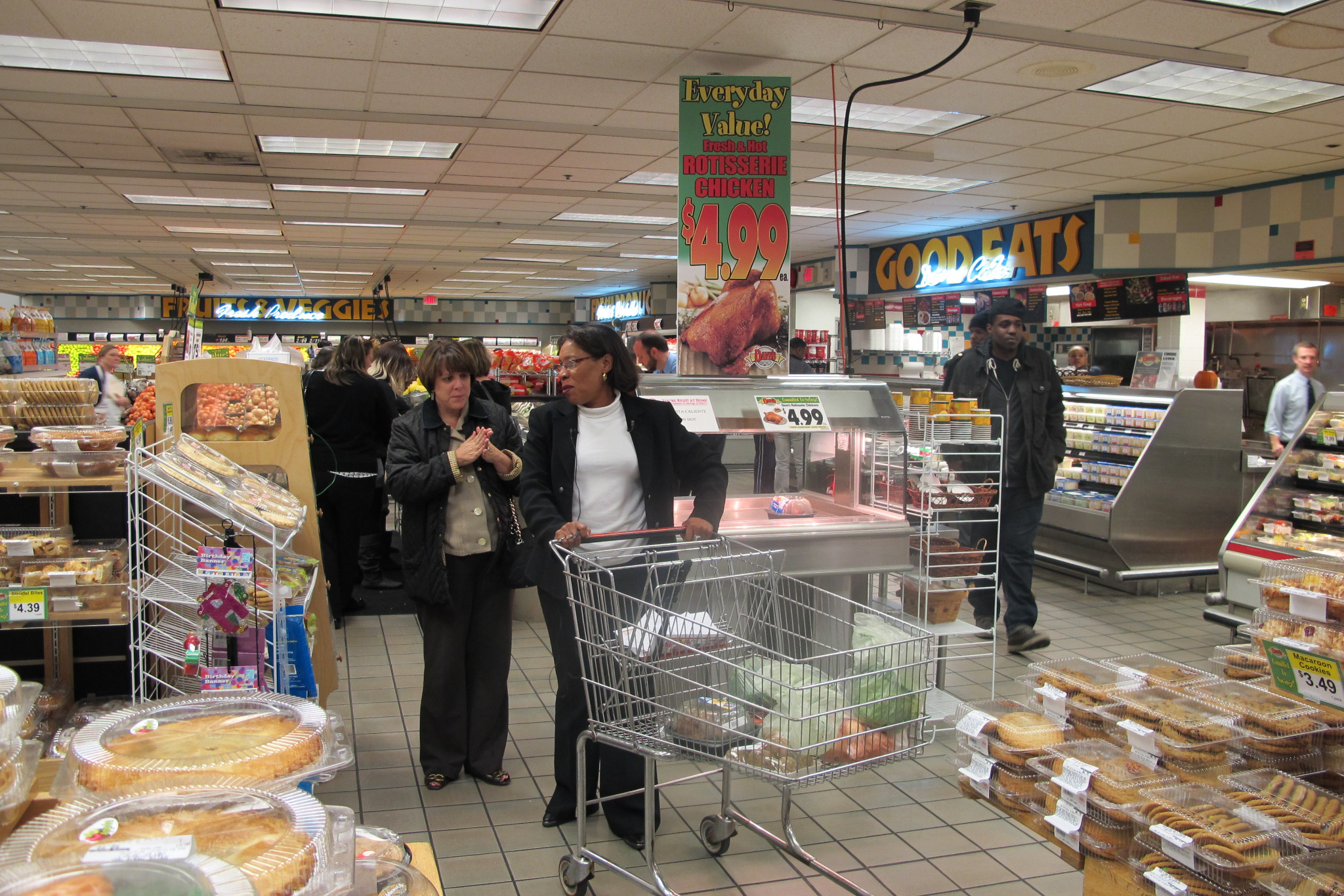 Marcia Fudge and Anne Goodman stand with a shopping cart inside a grocery store.