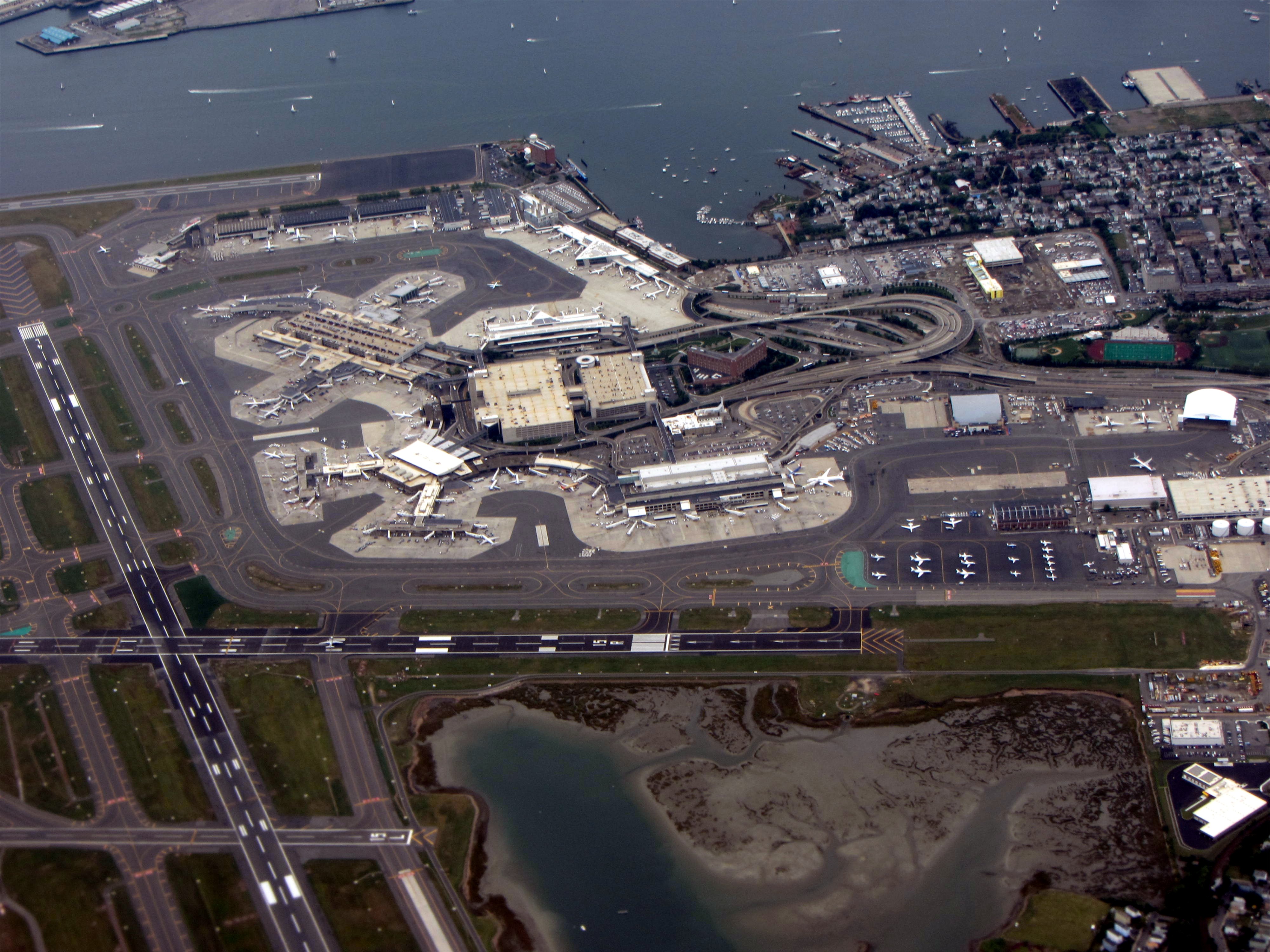 An aerial view of Logan Airport runways and terminals beside Boston Harbor.
