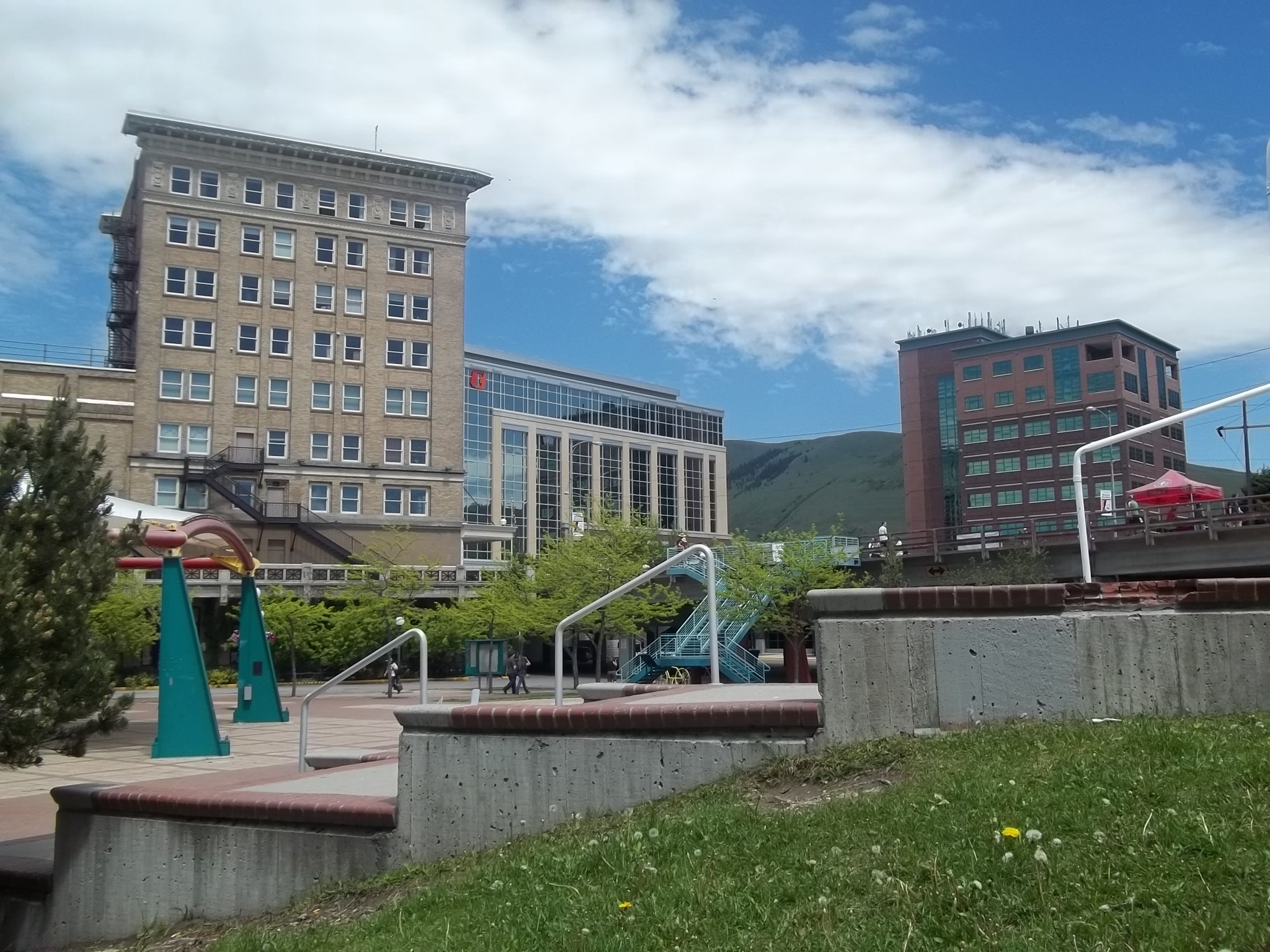 Archive view of downtown Missoula buildings, a plaza and steps, with a hillside behind them.