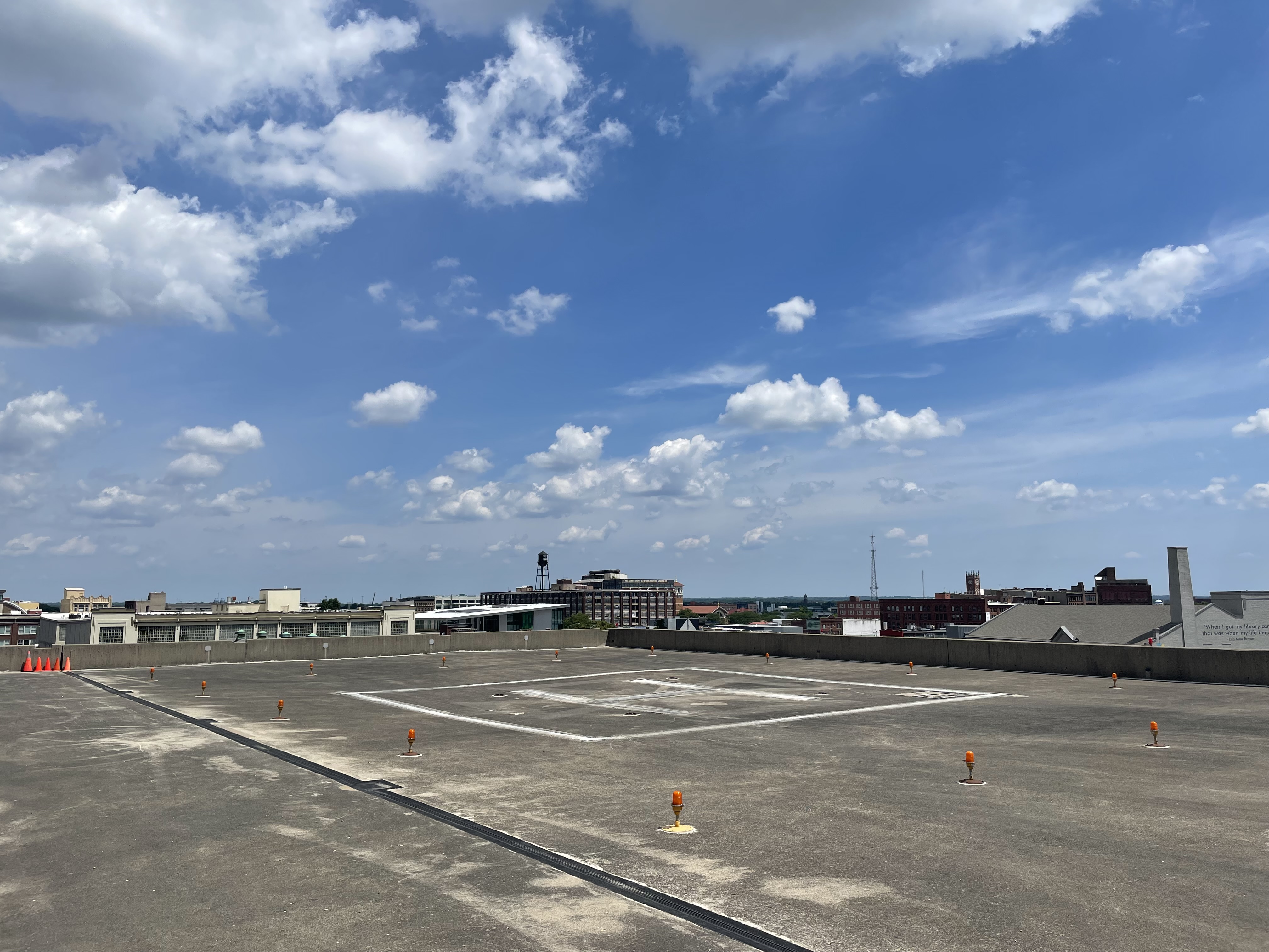 A rooftop helicopter landing pad marked with an H above a city skyline.